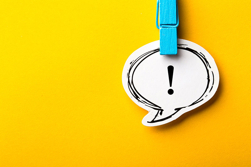 Sprechblasen-Symbol mit Ausrufezeichen vor gelbem Hintergrund.