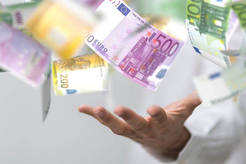 FDP-Rodgau-Kritik-an-Finanzpolitik Euro-Banknoten fallen symbolisch über einer ausgestreckten Hand.