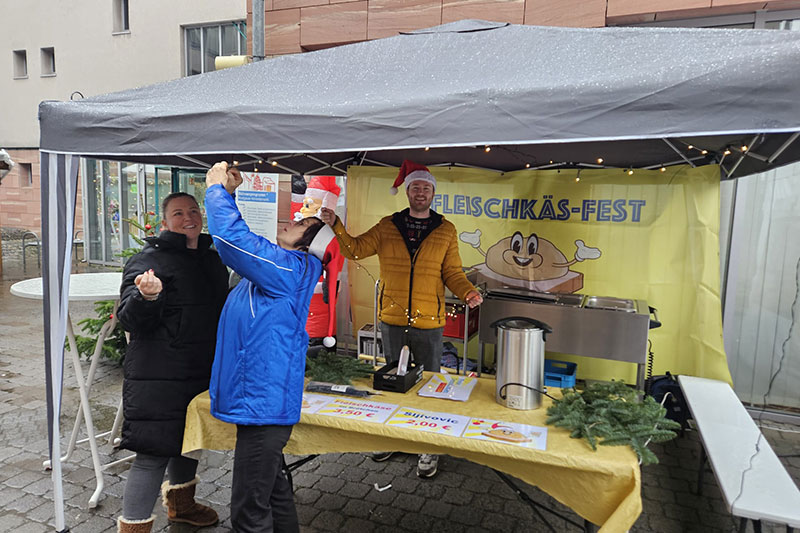 Mitglieder der FDP Rodgau haben sichtlich Spaß am Stand auf dem Weihnachtsmarkt in Jügesheim und verkaufen Speisen und Getränke.
